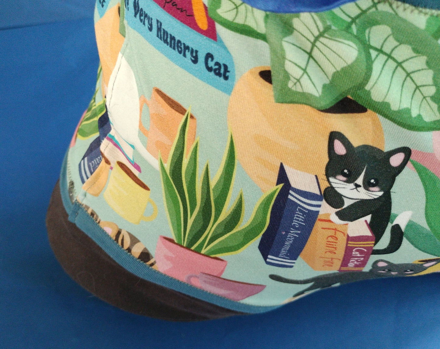 A section of the design showing a sad Oreo cat with houseplants, mugs & books